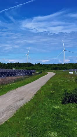 aerial rising shot reveals a solar farm and modern wind turbines in the lush latvian countryside, showcasing clean renewable energy and rural development