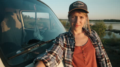 portrait of young pretty woman standing by van at lakeside