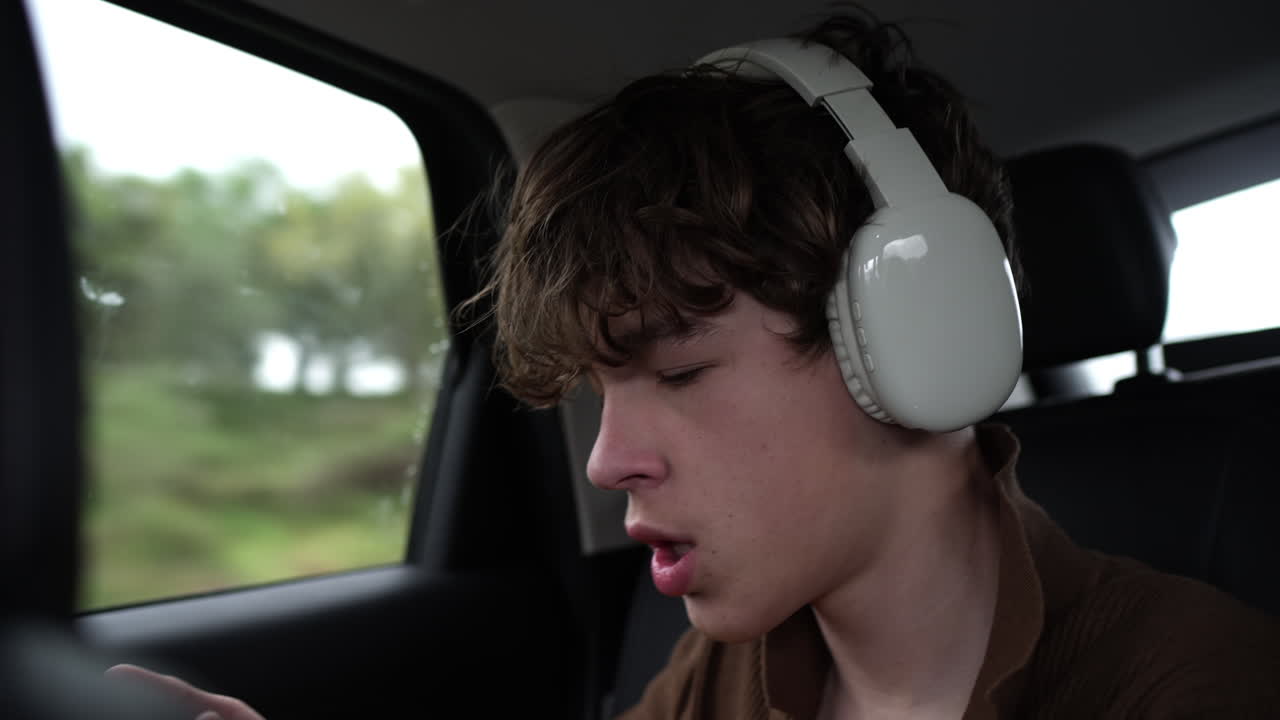 Young man listening to music with headphones in moving car