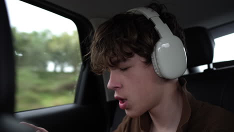 young man listening to music with headphones in moving car