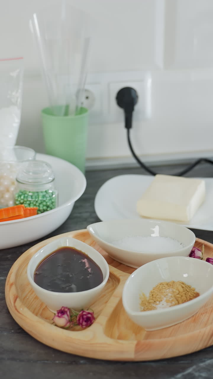 현대적 인 주방 카운터 은 향신료, 설탕, 나무 트레이 에 소스 를 담은 세라 그, 접시 에 버터, 재료 를 담은 유리 항아리, 유리 비, 차 비 를 포함 하고 있다