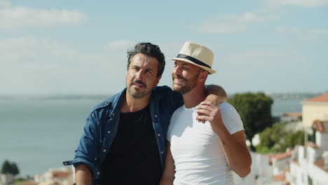 hombre homosexual feliz sentado y abrazando el hombro de su amante con vistas increíbles