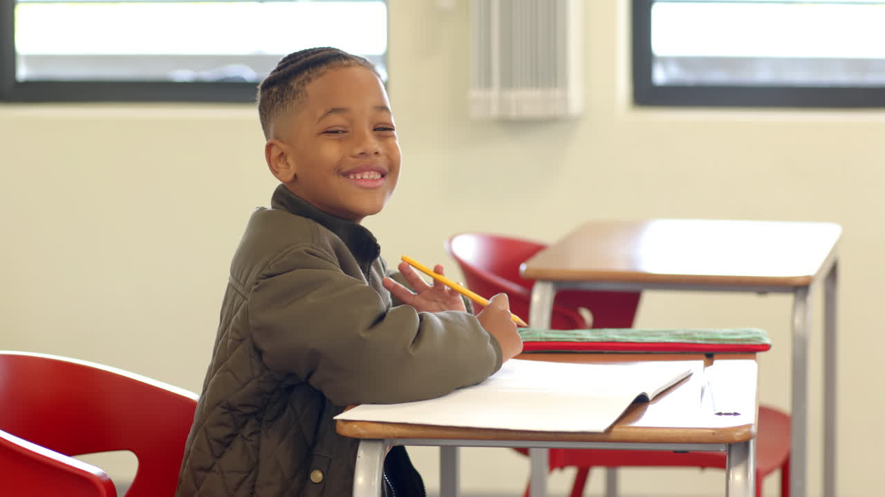 In classroom, young boy writing in notebook, concentrating on schoolwork