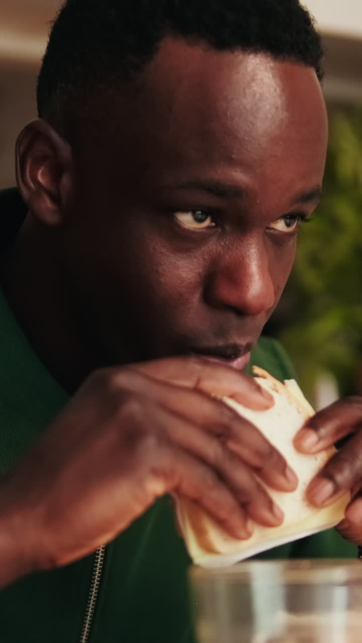 Jovem Africano Comendo Sanduíche e Bebendo Suco de Laranja
