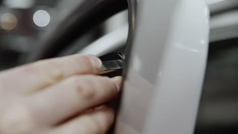 extreme close-up following a hand while precisely cutting the plastic protective film on a car