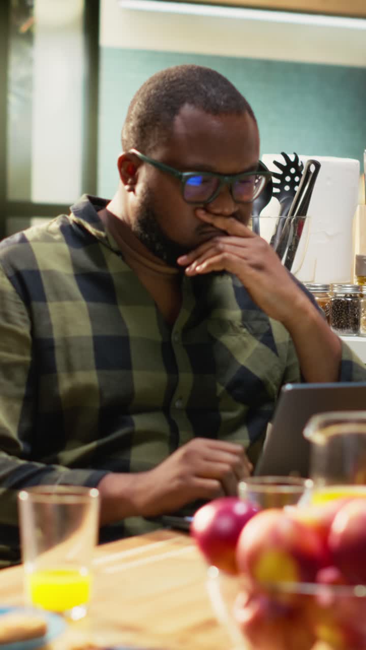 Vertikal video: Travel afroamerikansk arbeidende far som skriver på laptop ved bordet med familien sin
