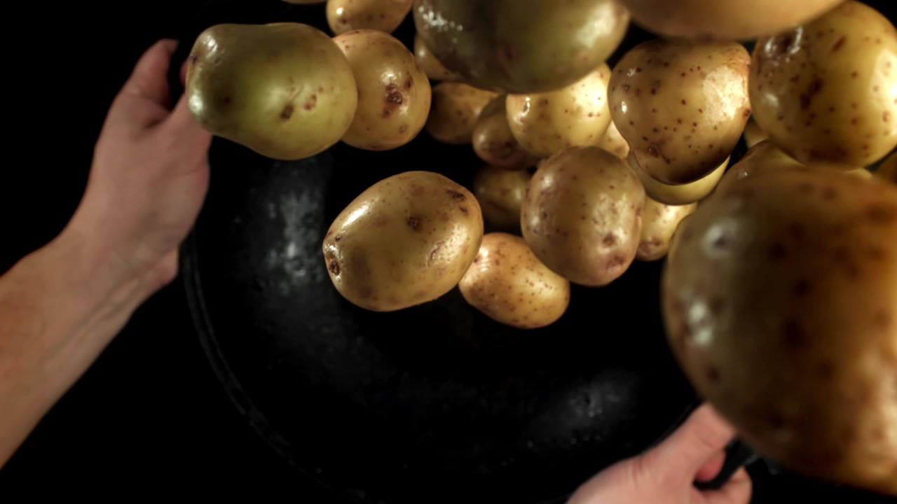 Patate fresche che saltano da una padella al rallentatore.