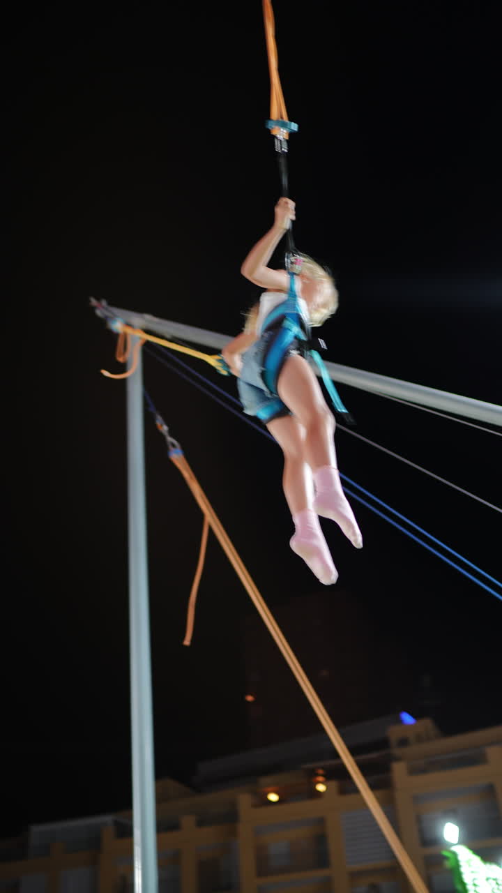 Child enjoying bungee trampoline at night