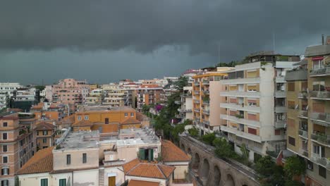 aerial drone forward moving shot of residential buildings along hilly terrain with dark rain clouds passing over the city of rome in italy