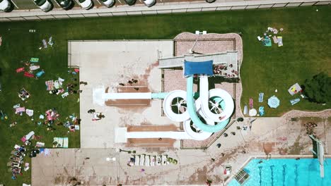 drone disparado directamente por encima de un doble tobogán de agua retorcido en una piscina pública al aire libre