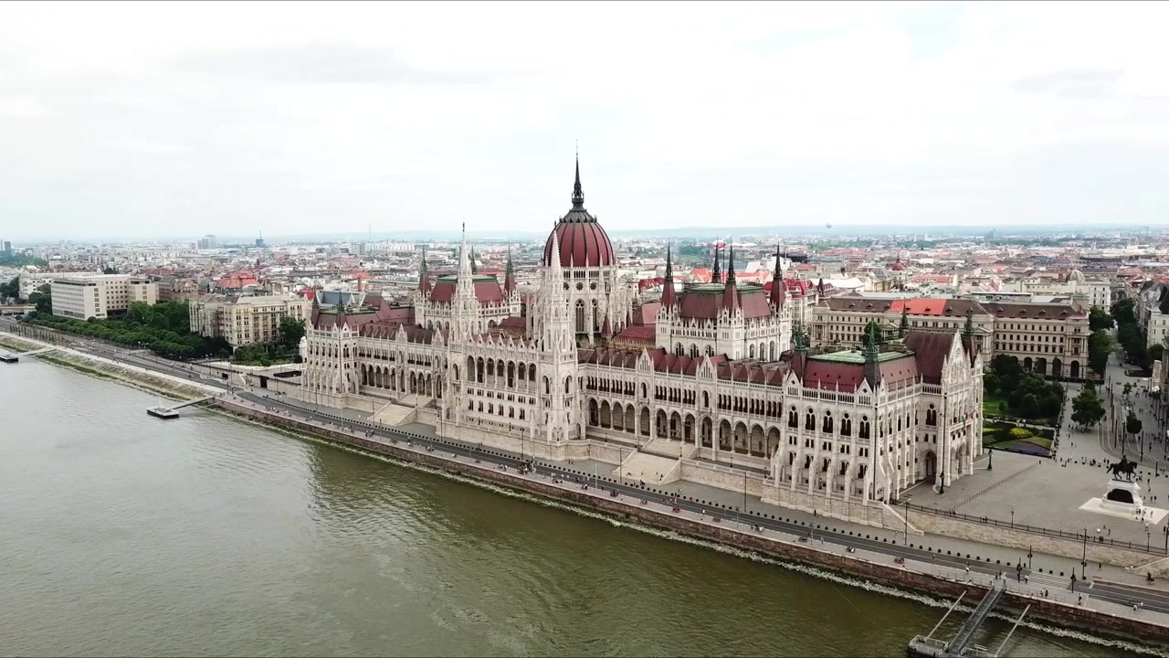 Vista aerea dell'iconico Palazzo del Parlamento Ungherese a Budapest, Ungheria, situato lungo il fiume Danubio, caratterizzato dalla sua architettura neogotica, dalla cupola rossa e dal paesaggio urbano circostante.