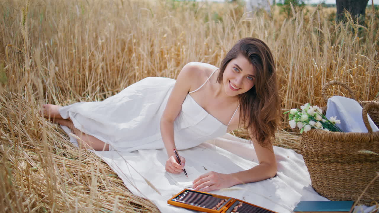 художница рисует эскизную тетрадь луг пикник. улыбающаяся женщина кладет одеяло