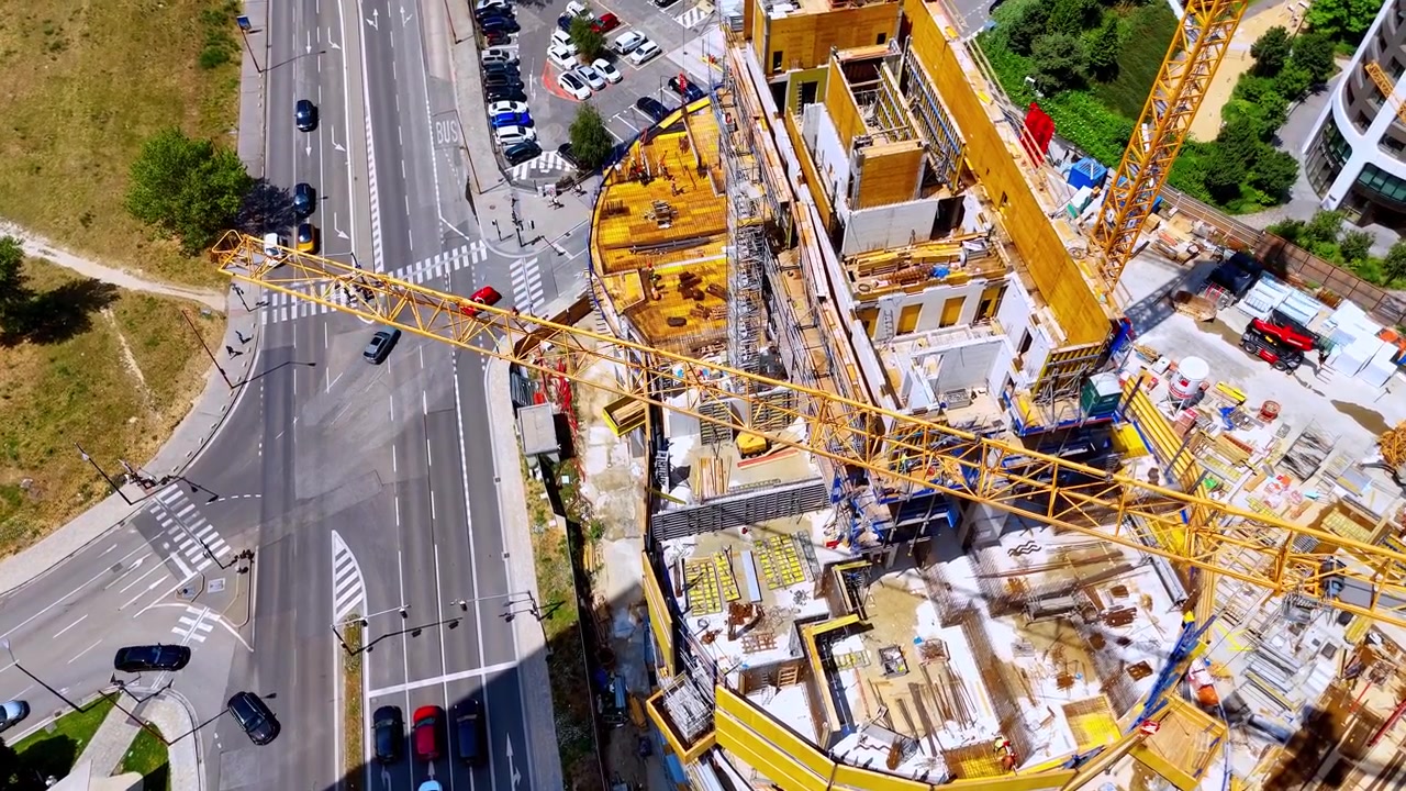 Bratislava, Slovacchia, 2 giugno 2026: Prospettiva aerea di un cantiere edile, Bratislava, Slovacchia. Cattura schermi di sicurezza gialli, bracci di gru e auto che guidano su una strada asfaltata.