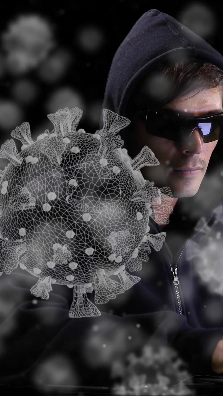 Animation of a hacker hooded man over macro COVID-19 cells floating
