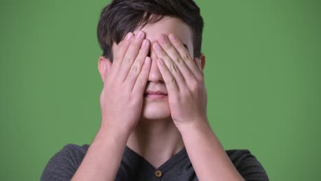 young handsome iranian teenage boy against green background