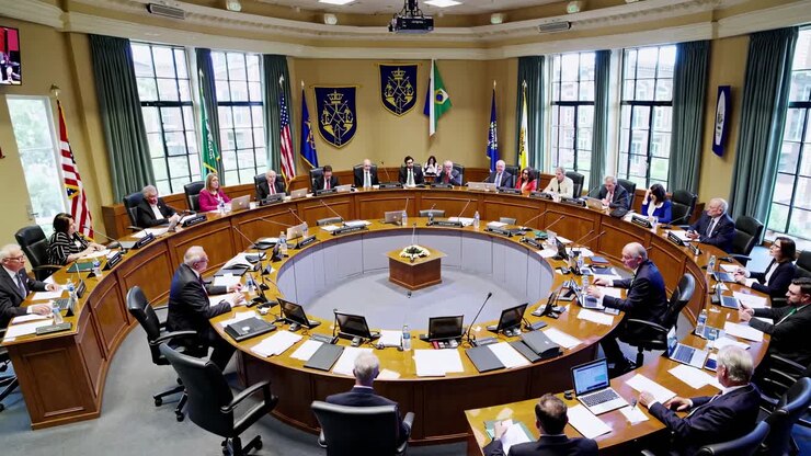 A wide-angle video captures a formal meeting in a circular conference room, showcasing officials