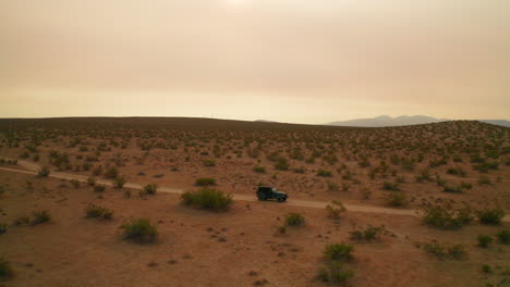 jeep parked in the lonely and harsh landscape of the mojave desert wilderness - aerial view