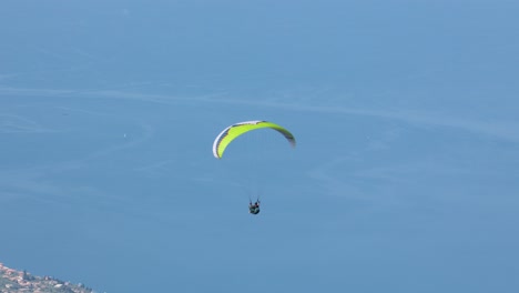 disparo de seguimiento de un solo hombre en parapente sobre el lago garda en italia en verano