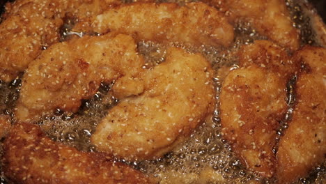 Crumbed-breast-chicken-tenderloins-fried-in-peanut-oil-in-a-pan
