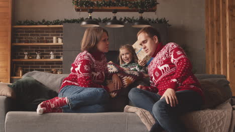 Niña-Dando-Un-Regalo-Sorpresa-A-Sus-Padres-El-Día-De-Navidad-En-Casa-1