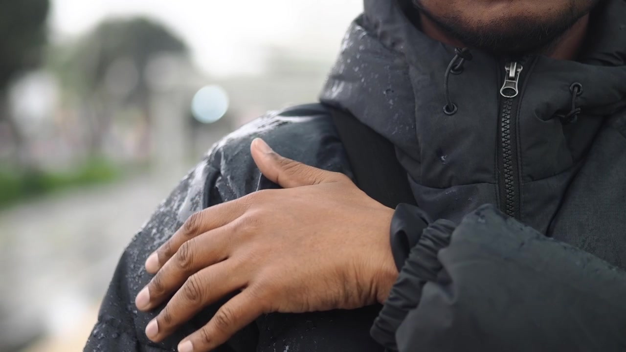 Person Touching Wet Shoulder of Black Puffer Jacket in Rain