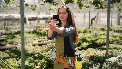 redhead woman gardener with smartphone shoots video and tells