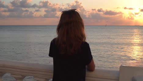 Girl watching sunset over the ocean