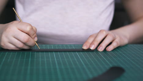 tailor draws dots on leather strip with silver iron pipe