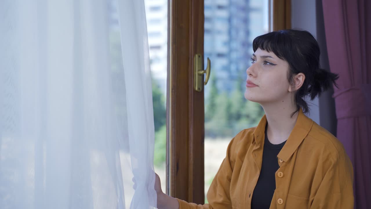 집의 커튼을 닫는 젊은 여성.