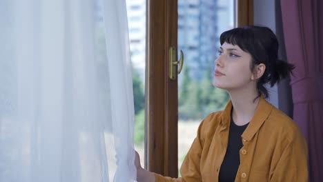 la joven que cierra las cortinas de la casa.