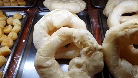 large tapioca flour donuts being displayed at a brazilian bakery showcase.