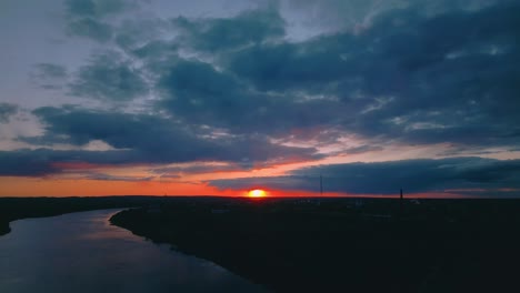 sun drops below daugavpils, painting the daugava river and sweeping storm clouds with deep orange and indigo hues. daugavpils, latvia (daugavpils, latvija)