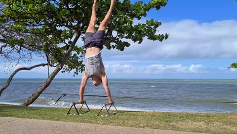 young adult male practising handstand on trinity beach, cairns