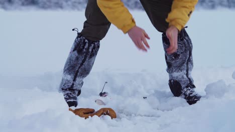 portrait of a man bent down rubbing hands with snow in winter