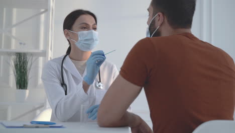 female doctor uses a cotton swab to test a male patient for coronavirus.