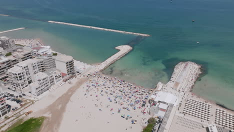 Imágenes-Aéreas-Que-Giran-Alrededor-De-La-Playa-Y-El-Verde-Mar-Adriático-Que-Muestran-A-Los-Turistas-Tomando-El-Sol-Y-Nadando-En-Bari,-Italia