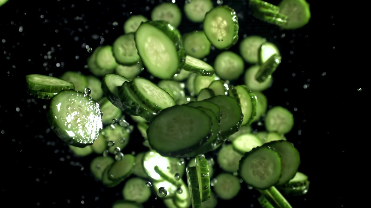 Fatias de Pepino Fresco Caindo com Respingos de Água em Super Câmera Lenta