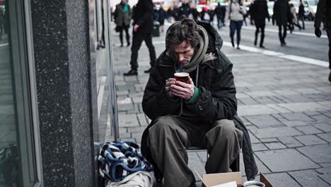 homeless man drinking coffee on the street