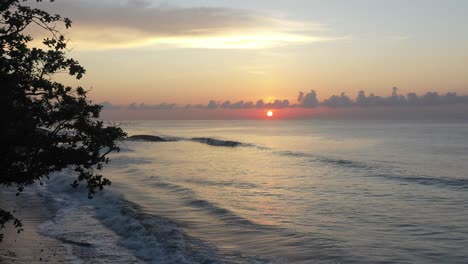 Drone-Aéreo-Volando-Sobre-Un-Cocotero-En-La-Playa-Con-Olas-Rompiendo-Durante-El-Amanecer-En-Bali-Indonesia