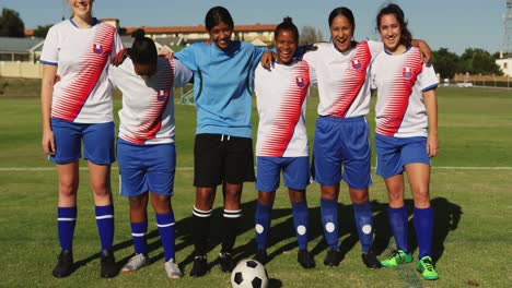 Female-soccer-team-standing-arm-to-arm-on-soccer-field.-4k