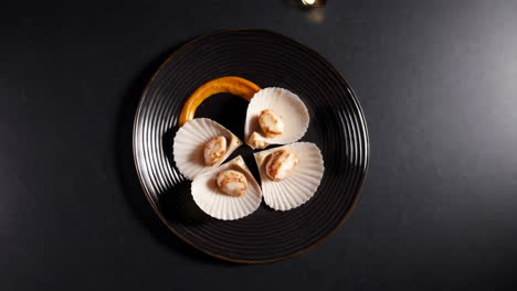 seared scallops in shells with flashlight illumination on a dark plate