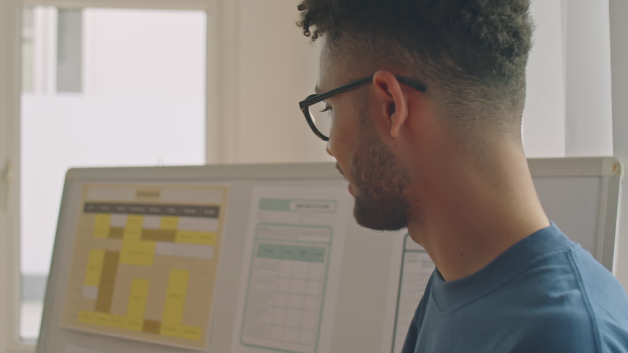 Young Male Teacher Speaking by Whiteboard in Classroom