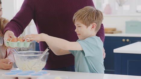 primer plano de padre con dos hijos en la cocina en casa divirtiéndose horneando pasteles juntos