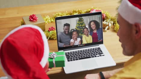 Kaukasischer-Vater-Mit-Sohn-Nutzt-Laptop-Für-Weihnachtsvideoanruf-Mit-Lächelnder-Familie-Auf-Dem-Bildschirm