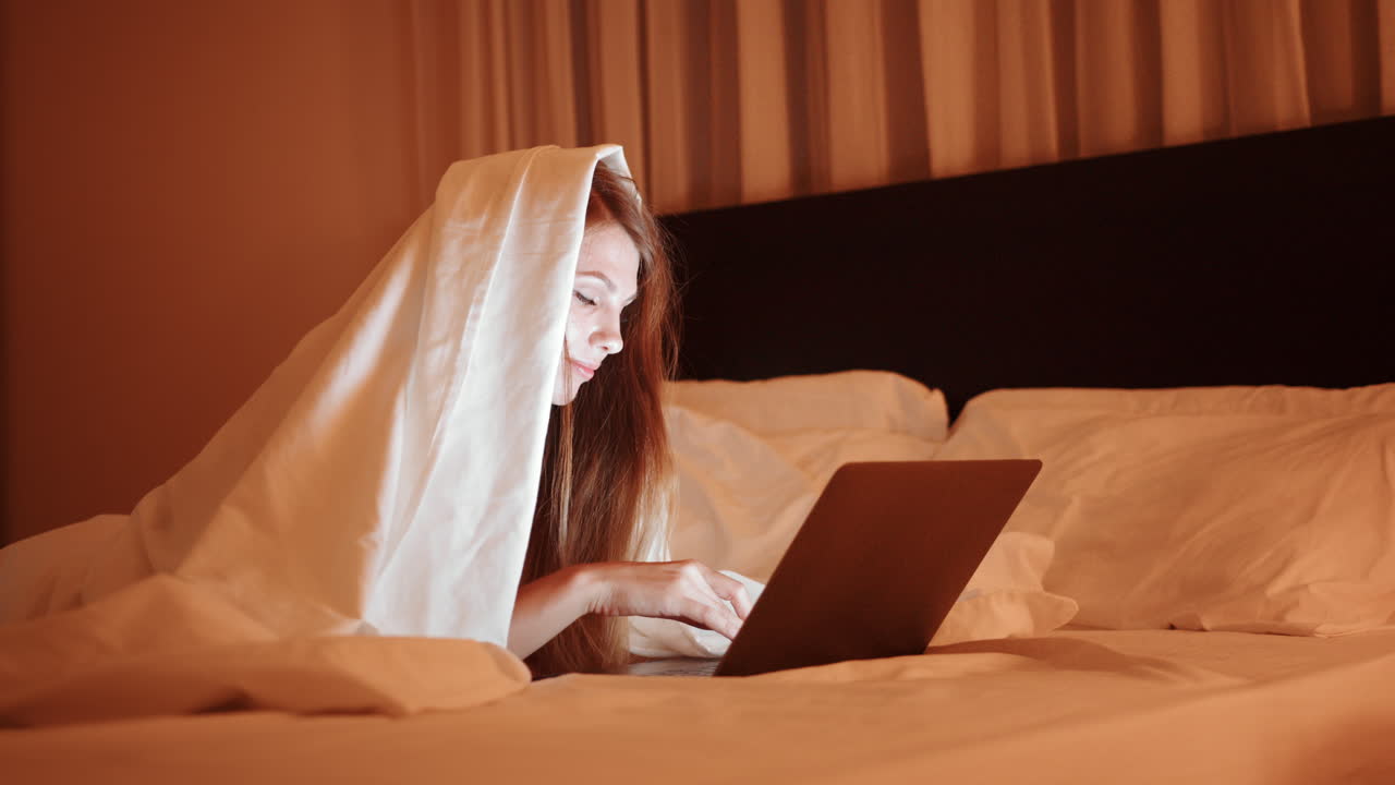 밤에 침대에서 노트북으로 일하는 여자