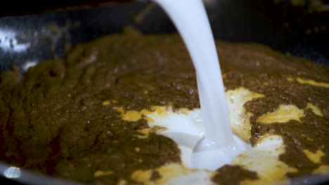 Pouring-White-Coconut-Milk-from-Can-into-sizzling-Brown-Massaman-Curry-Paste