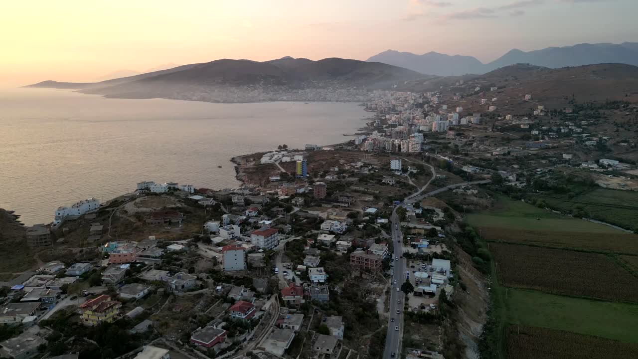 A cinematic drone captures a city by the waterfront, enveloped in a dramatic, moody atmosphere, where modern buildings meet the dark, serene waters and skies.