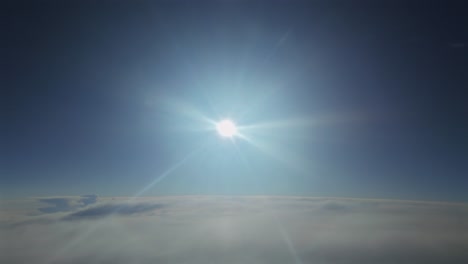 hyperlapse of a blinding and radiant sun shining above a layer of clouds. An aerial footage taken from a jet cockpit.