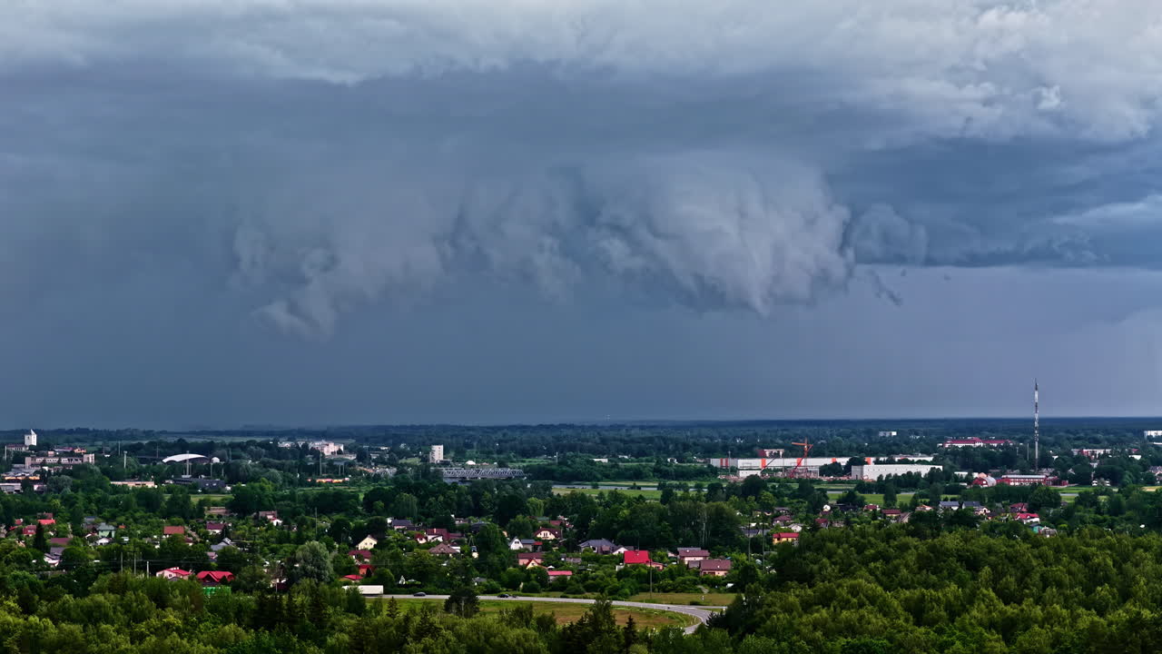 Aerial view of storm clouds forming over a small town surrounded by trees