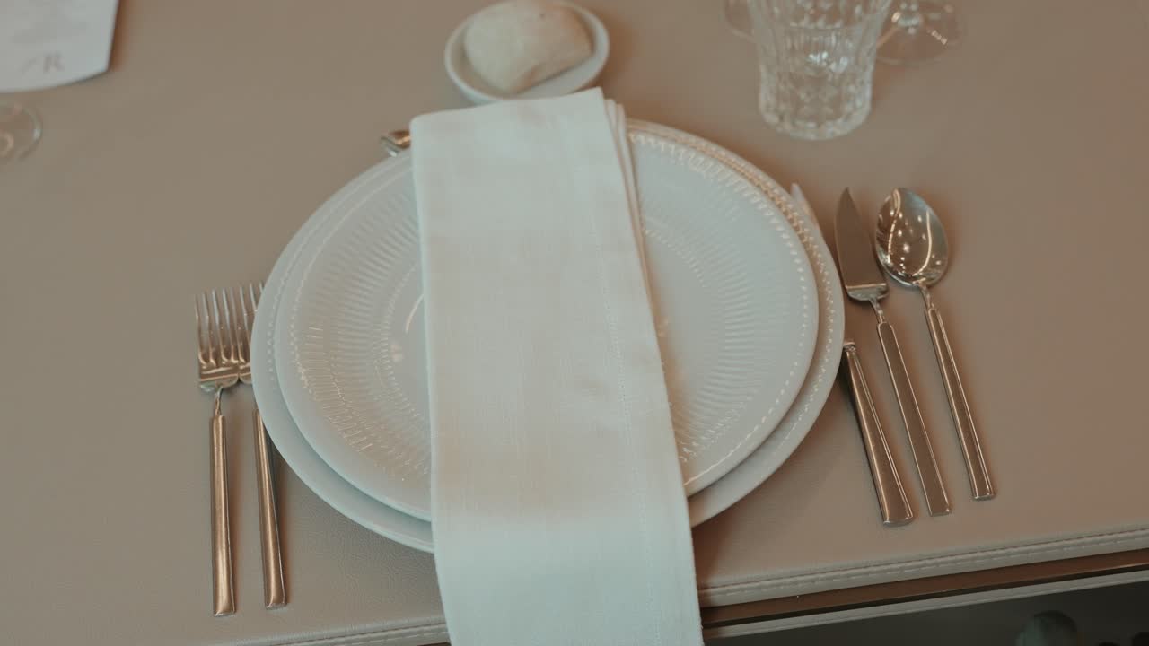 Disposición minimalista de mesa de comedor con platos, cubertería y servilleta doblada
